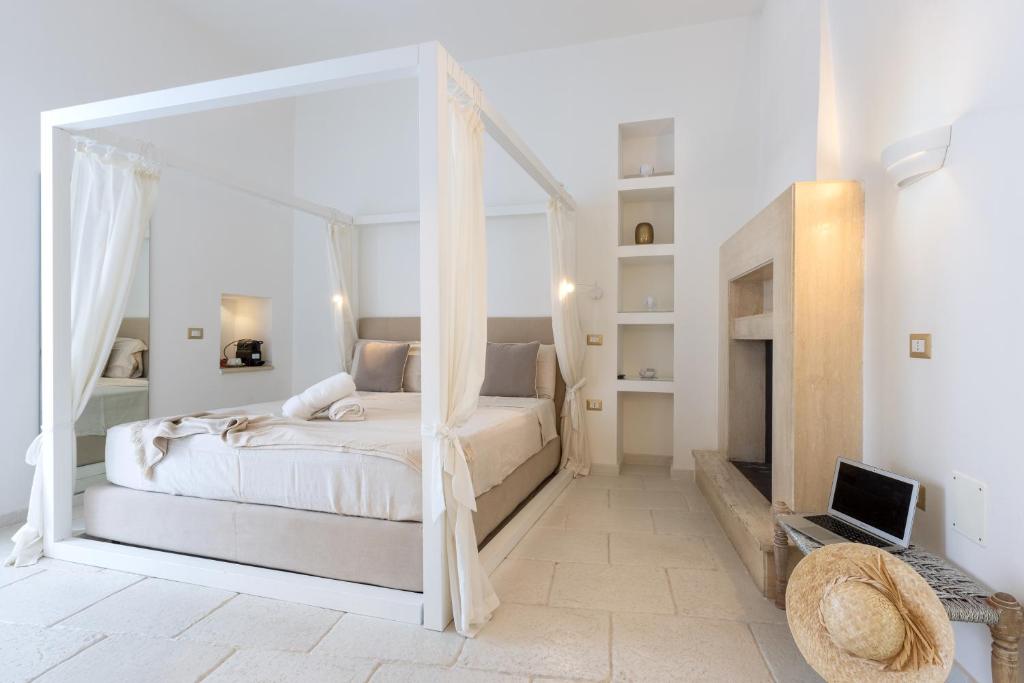 a white bedroom with a canopy bed and a fireplace at La Loggetta in Ugento