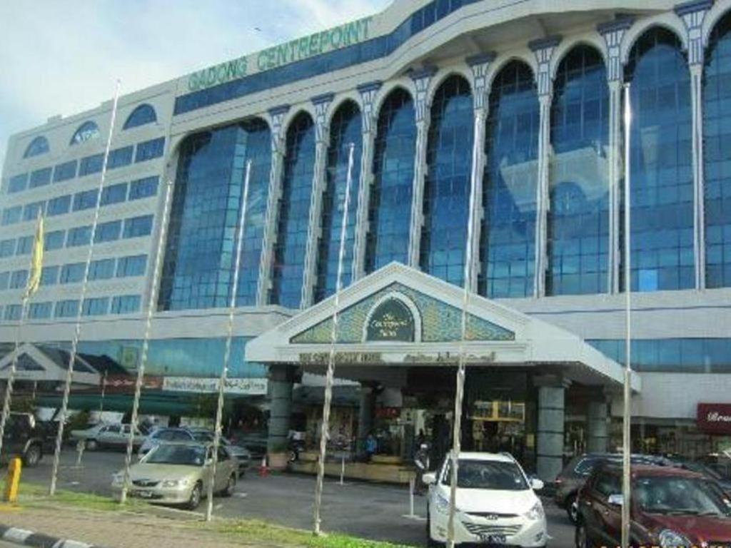 a large building with cars parked in a parking lot at The CentrePoint Hotel in Kampong Gadong