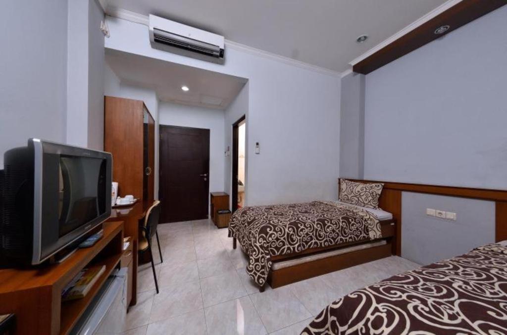 a hotel room with two beds and a flat screen tv at UNY Hotel in Demangan