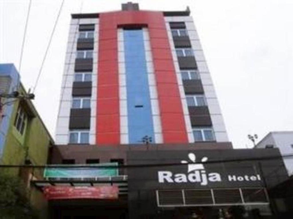 沙馬林達的住宿－Radja Hotel，一座高大的红色和白色建筑,有商店