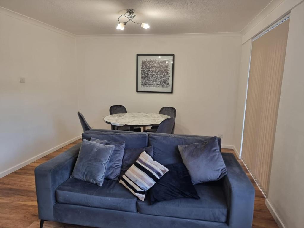 a living room with a blue couch and a table at Rehoboth Living in Thamesmead