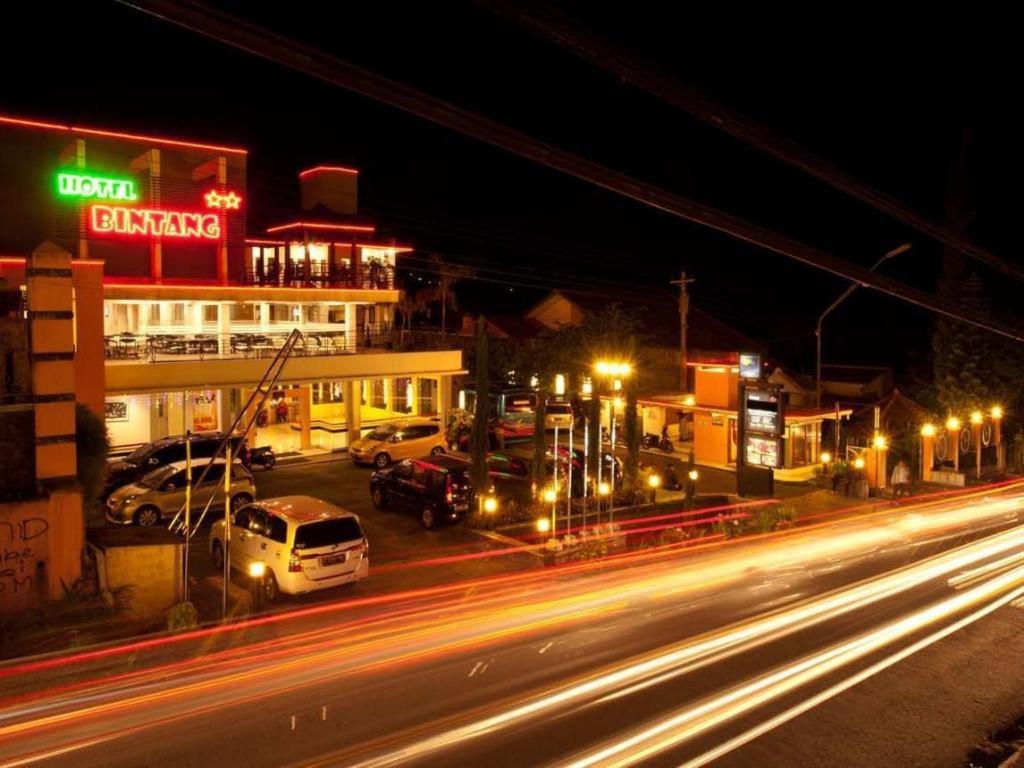 a city street at night with cars parked in a parking lot at Hotel Bintang Tawangmangu in Tawangmangu