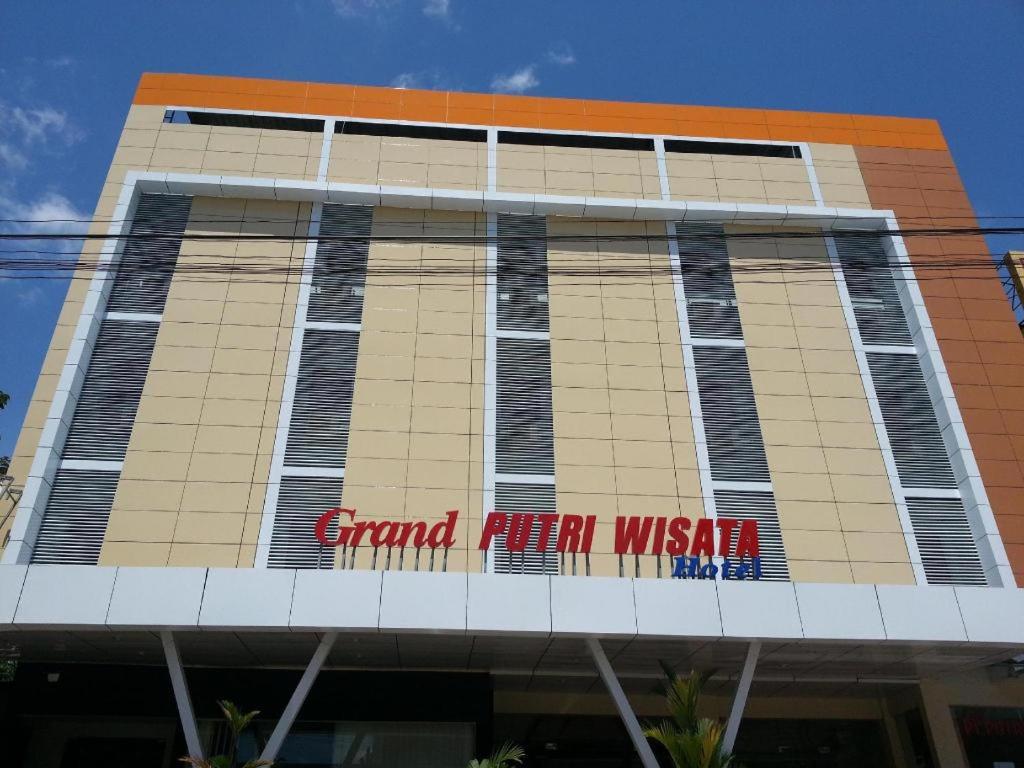 a building with a sign on the side of it at Putri Wisata Hotel in Puunggolaka