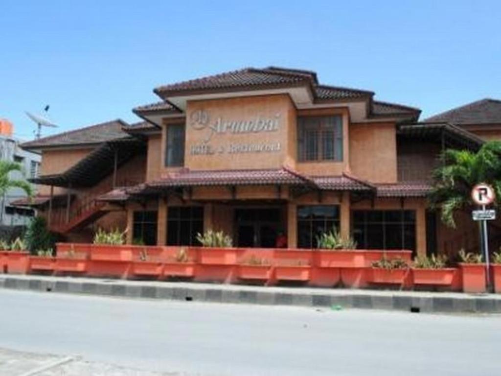 a restaurant with red chairs in front of a building at Hotel Arumbai in Boruku