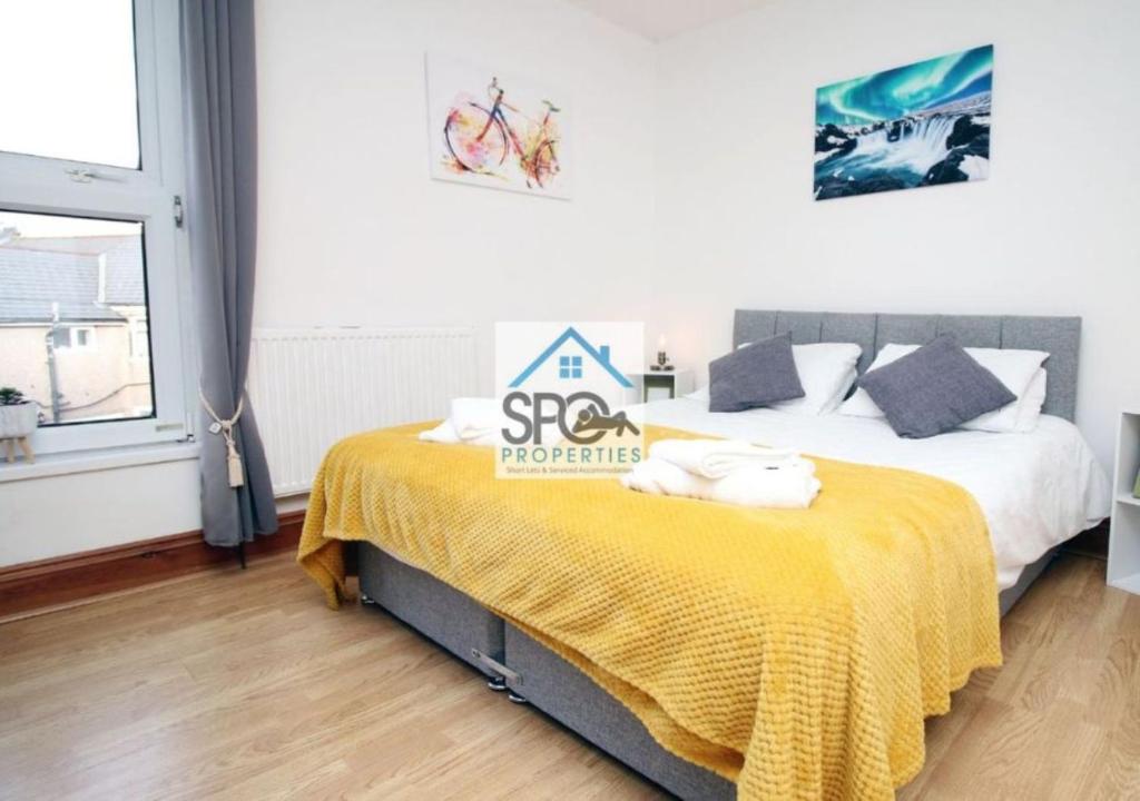 - une chambre avec un lit et une couverture jaune dans l'établissement Spacious 3BR Home-6 Guests-Business-Families-Netflix-Free Parking & WiFi, à Pontnewynydd