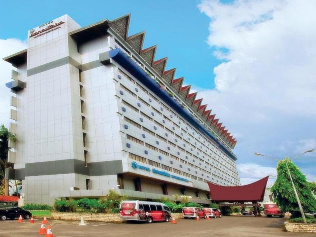 棉蘭的住宿－Danau Toba Hotel International，一座大型建筑,前面有汽车停放