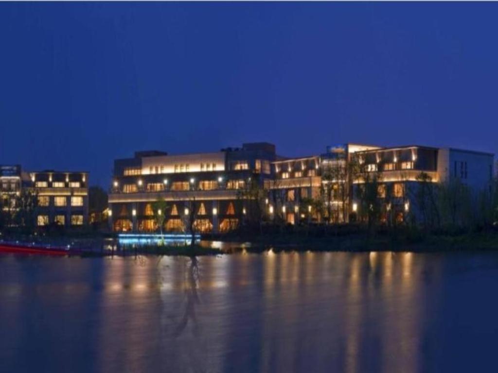 a lit up building next to the water at night at Changzhou Fudu Qingfeng Garden Hotel in Beigang