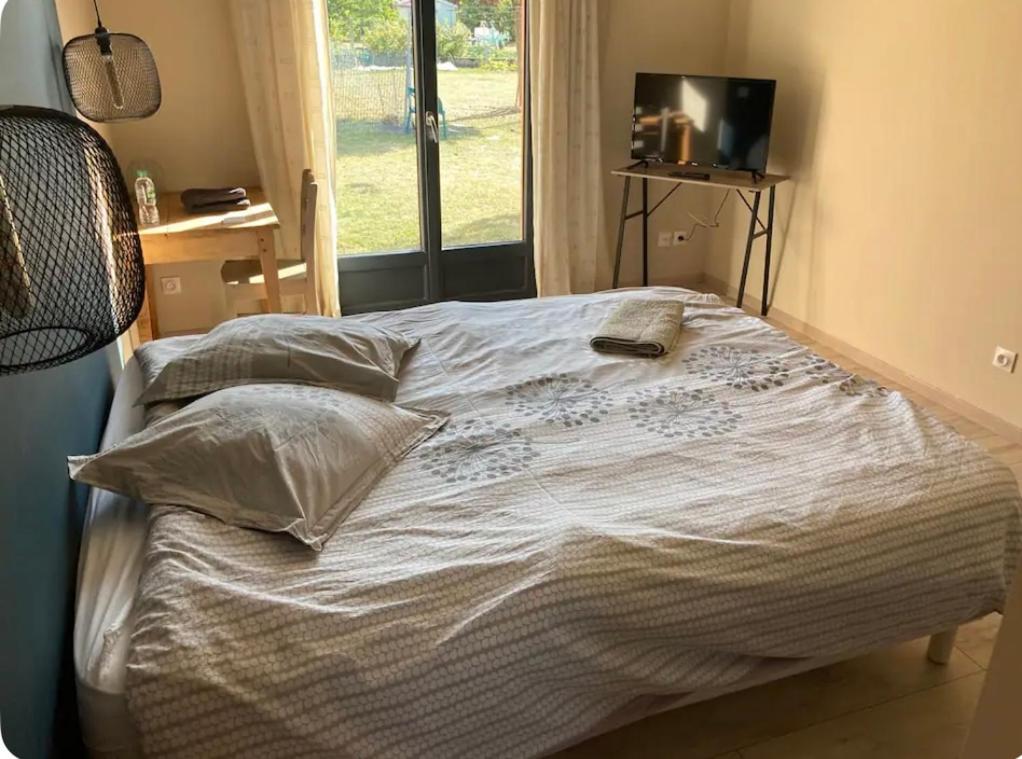 1 dormitorio con cama con almohadas y TV. en Chambre au calme en Creuzier-le-Vieux