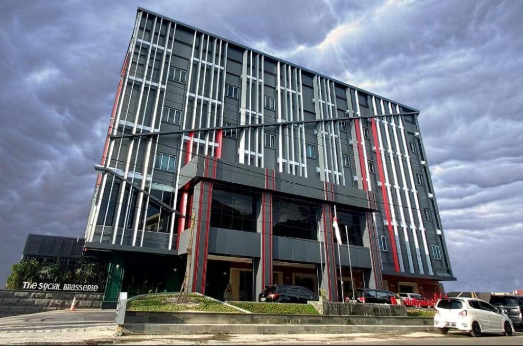 un grande edificio con macchine parcheggiate di fronte di New Hollywood Hotel a Pekanbaru