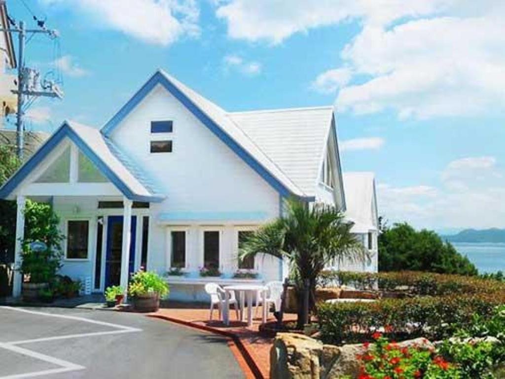 a white house with two white chairs in a parking lot at Country Inn The White Marine in Tonosho