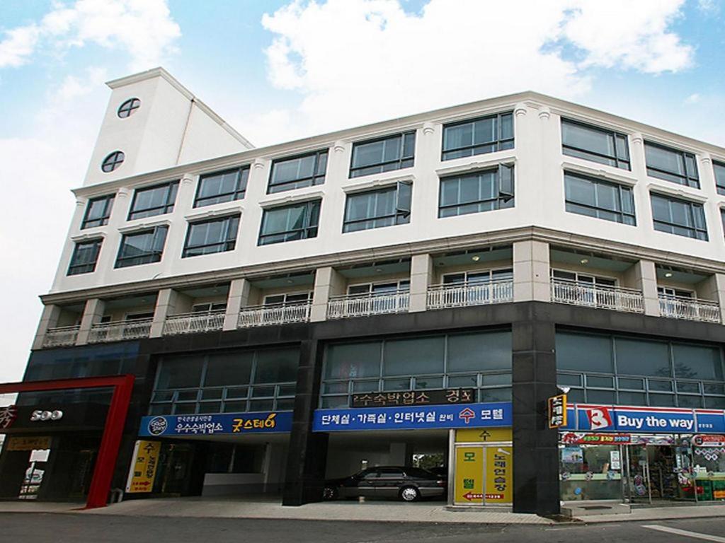 a large white building with a car parked in front of it at Goodstay Soo Hotel in Gangneung