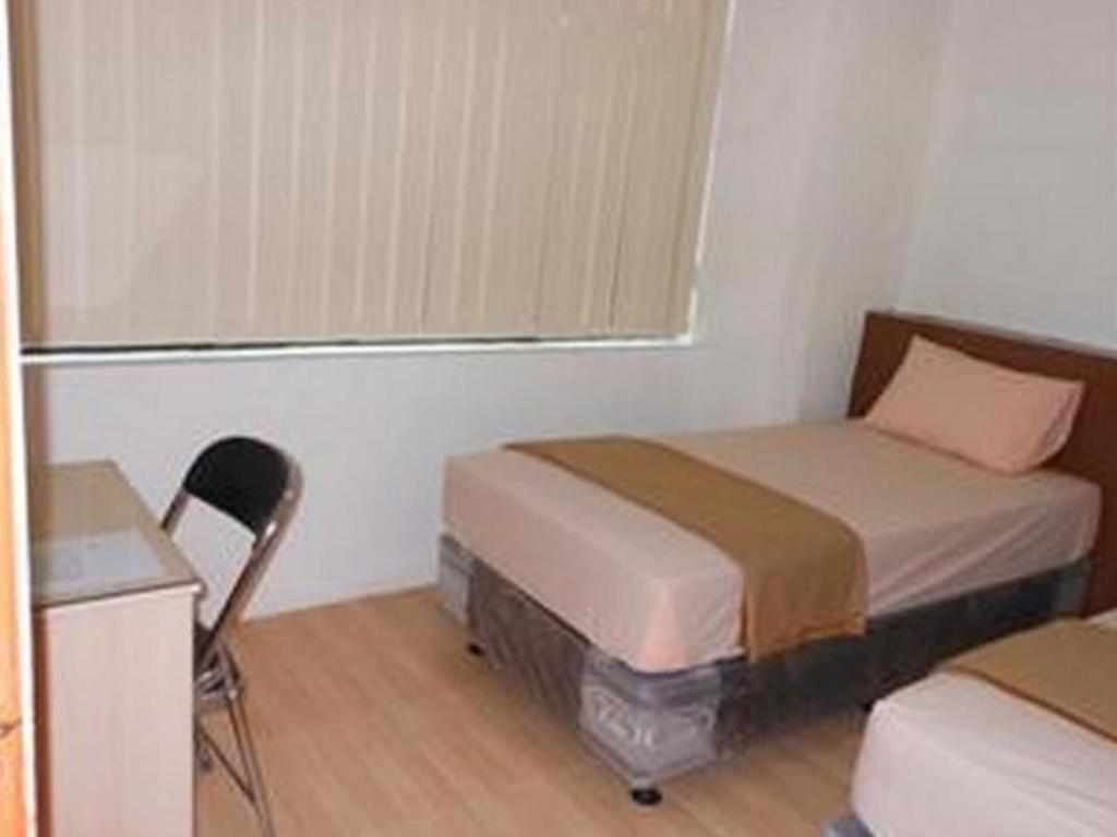 um quarto com uma cama, uma cadeira e uma janela em @thome em Sukodono