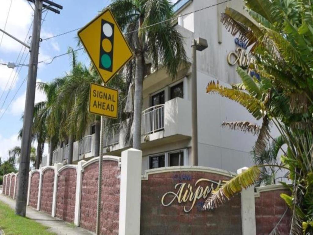 una señal de calle amarilla frente a un edificio en Guam Airport Hotel, en Tumon
