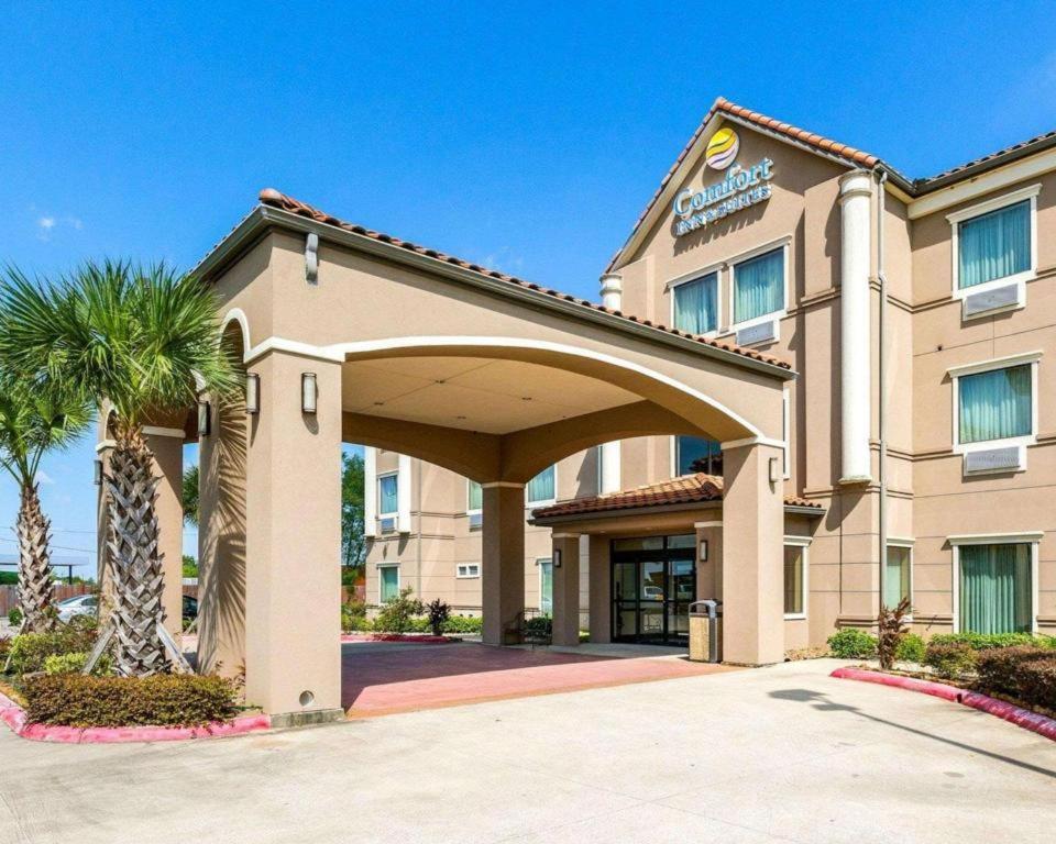 a hotel building with a palm tree in front of it at Comfort Inn & Suites in Winnie