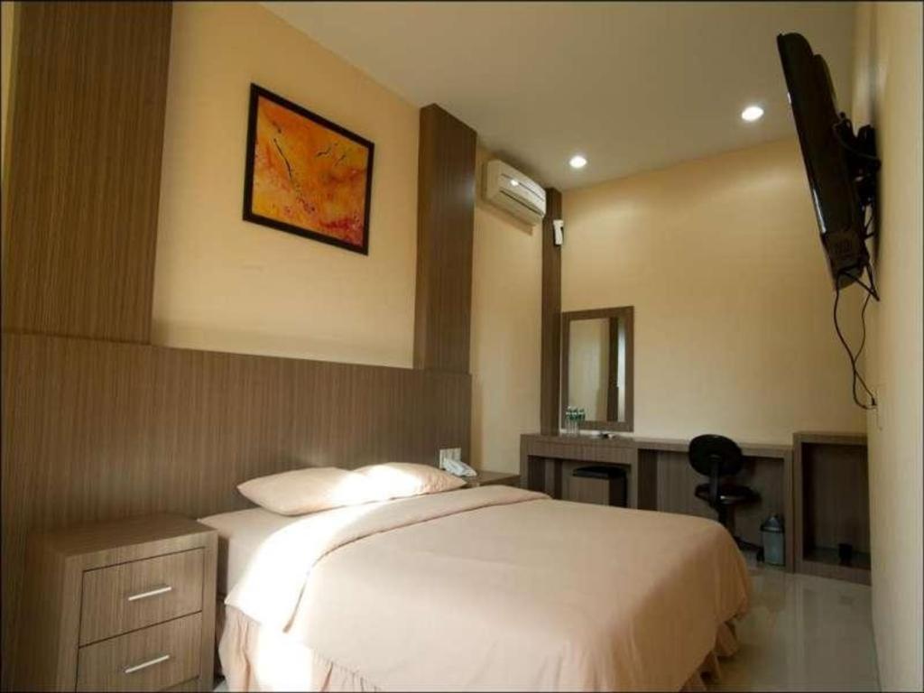 a bedroom with a bed and a television on the wall at Benteng Hotel Pekanbaru in Parit