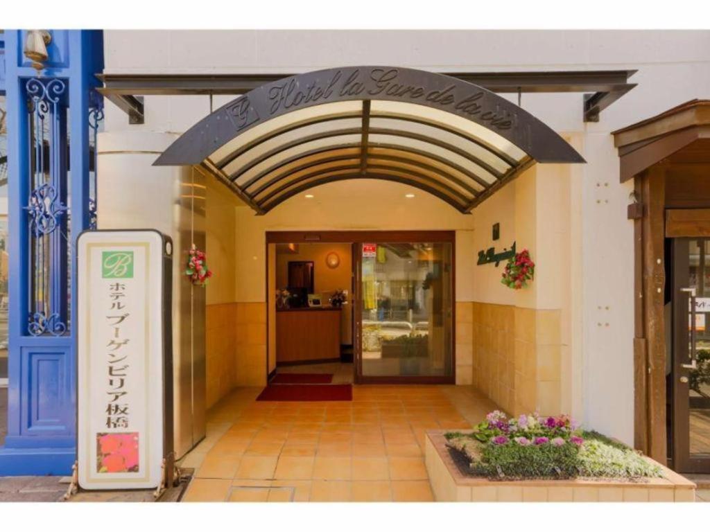 une entrée à un bâtiment avec un panneau sur celui-ci dans l'établissement Hotel Bougainvillea Itabashi, à Tokyo