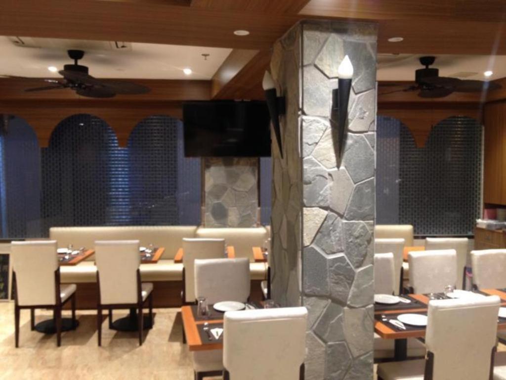 a dining room with tables and chairs and a stone wall at Hong Thai Hotel in Macau