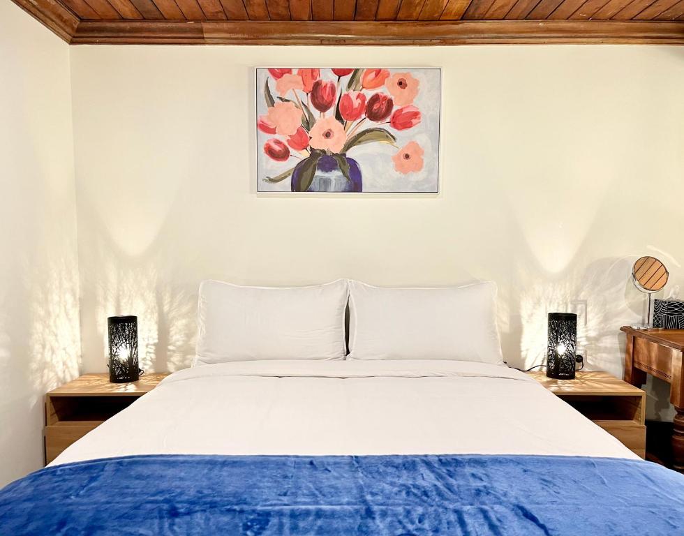 a bedroom with a bed and two lamps and a painting at Opoho Heritage Guest Suite in Dunedin