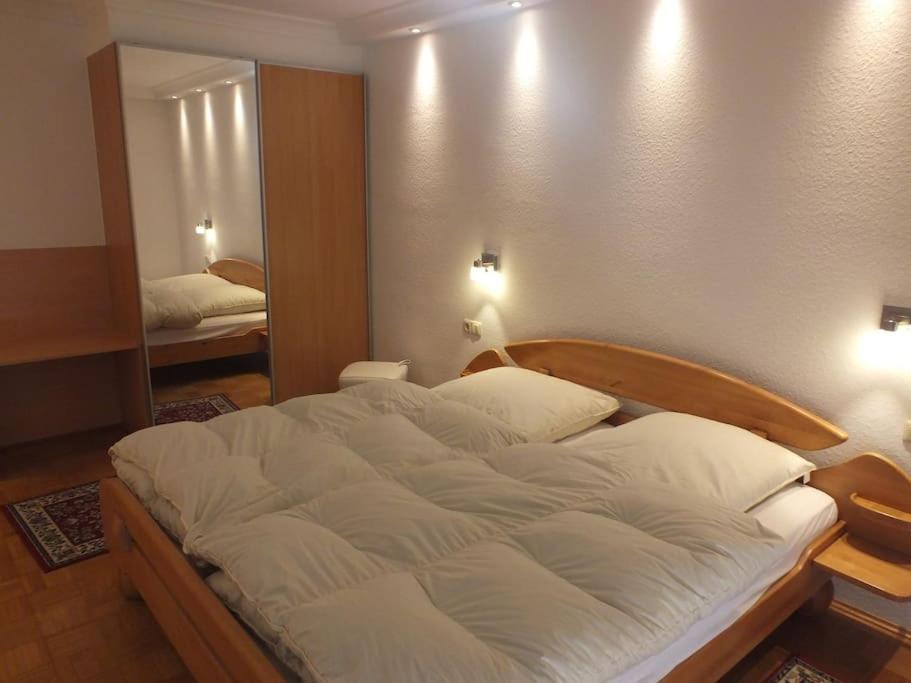 a large white bed in a room with a mirror at Ferienwohnung Jersemann in Steingaden