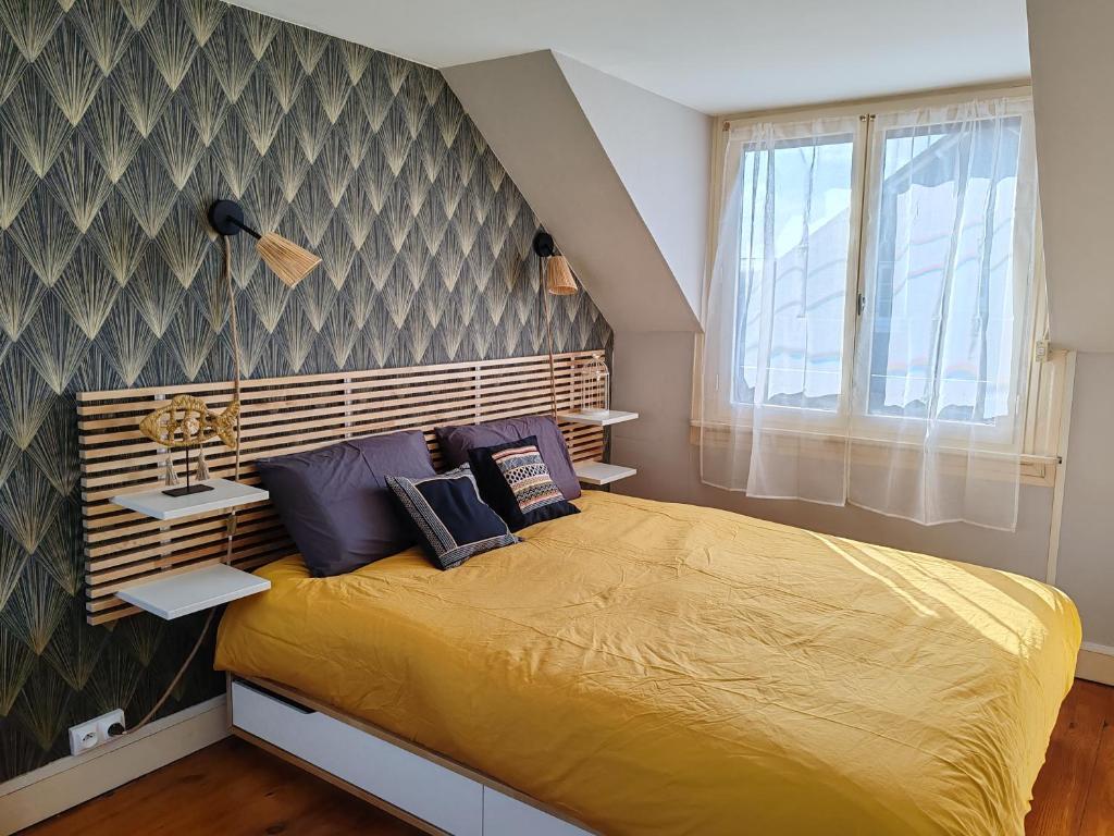 a bedroom with a large yellow bed with a wall at Villa Francette à 500m de la plage in Ouistreham