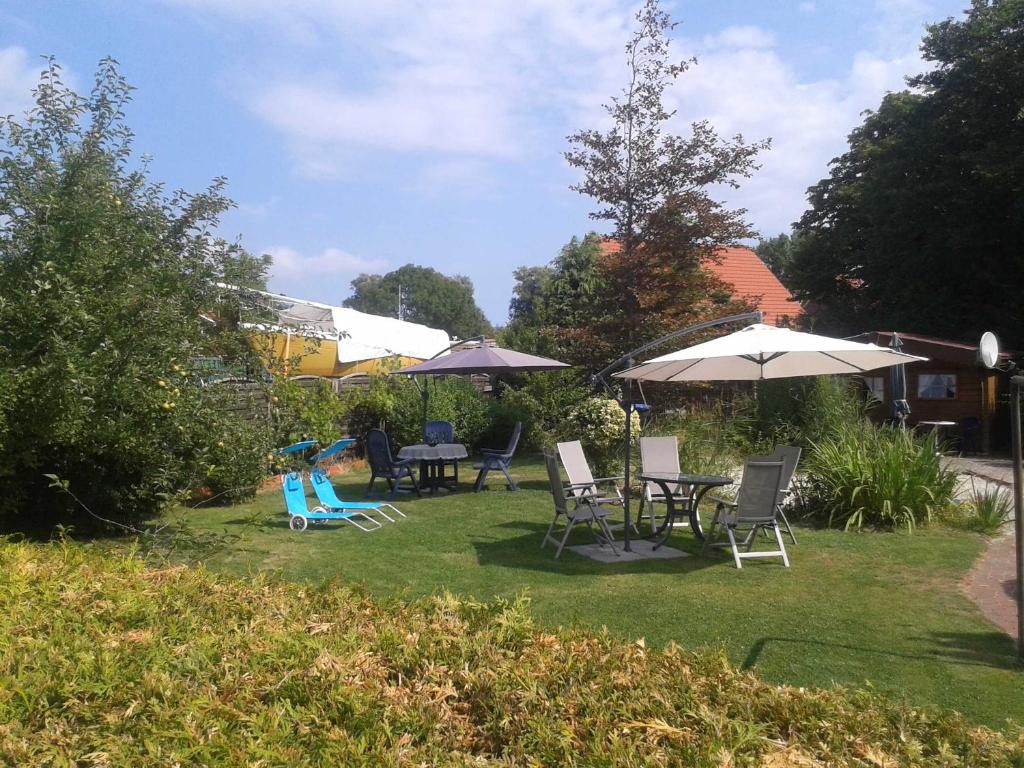 einen Garten mit Stühlen, Tischen und Sonnenschirmen in der Unterkunft Ferienanlage Blinkfuer in Dornumersiel
