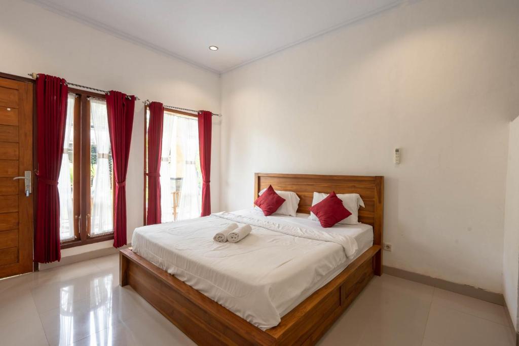 Schlafzimmer mit einem großen Bett und roten Vorhängen in der Unterkunft Omah Nusa Villa RedPartner in Nusa Penida