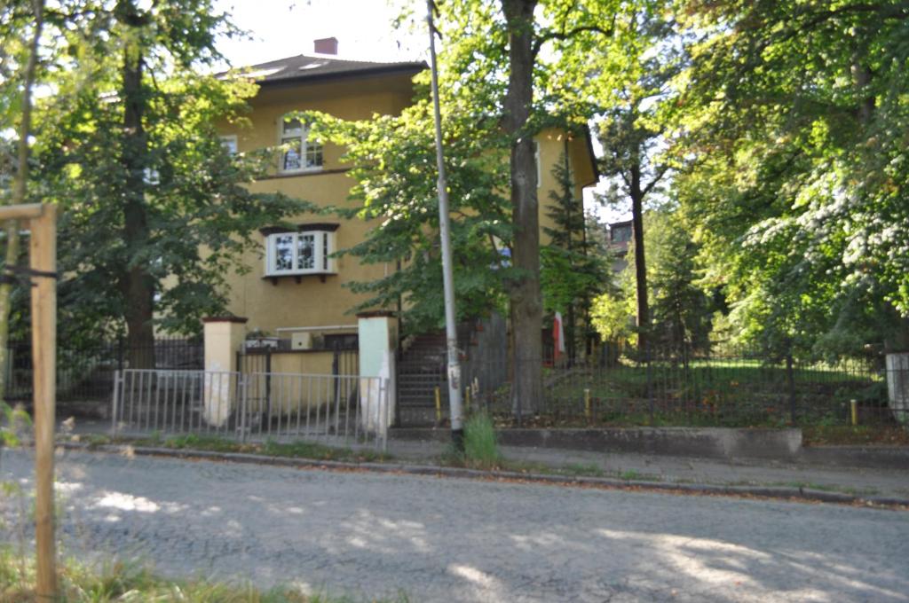 a yellow house with a fence in front of a street at Pod starymi lipami in Szczecin