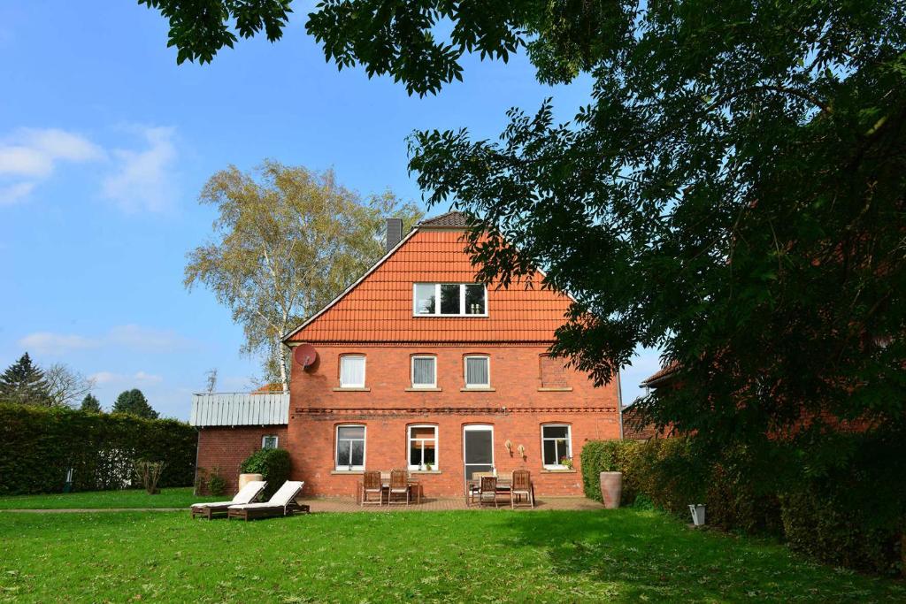 een groot bakstenen huis met stoelen en tafels in een tuin bij Weserlounge Apartments in Hessisch Oldendorf