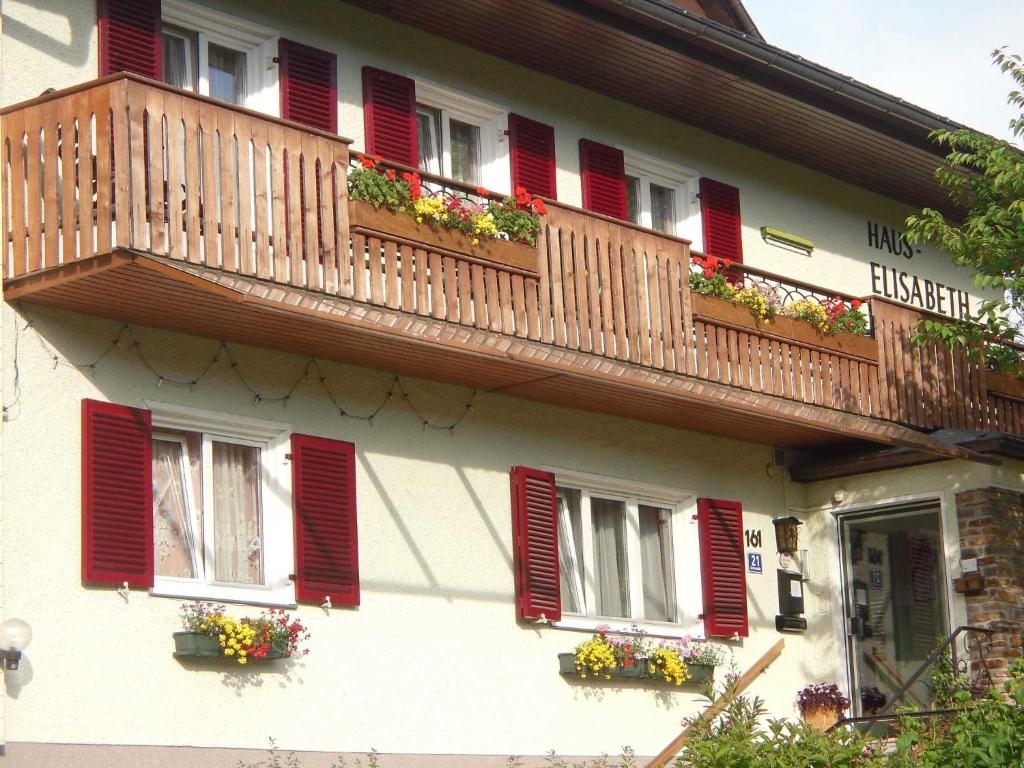 um edifício com janelas com persianas vermelhas e caixas de flores em Ferienwohnungen Haus Elisabeth em Bad Goisern