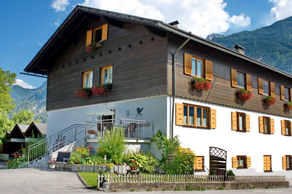 una grande casa in legno con fiori alle finestre di Haus Wallner a Dellach im Drautal