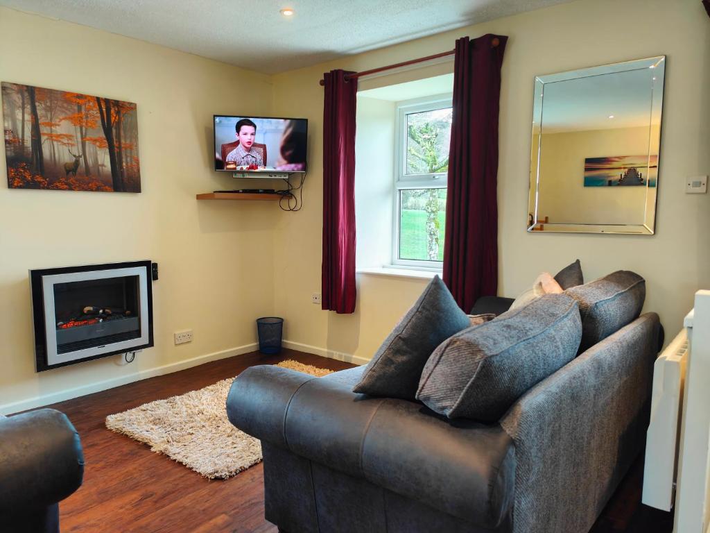 a living room with a couch and a television at Holiday Cottage 6 in Watermillock