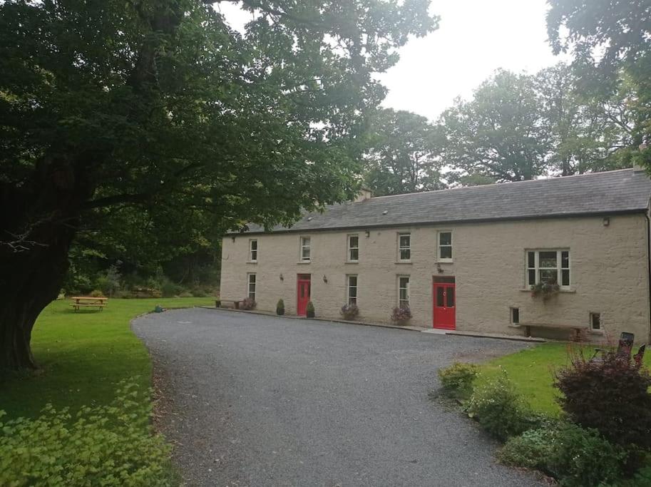 un edificio blanco con puertas rojas y una entrada de grava en Wood House Lodge, en Tipperary