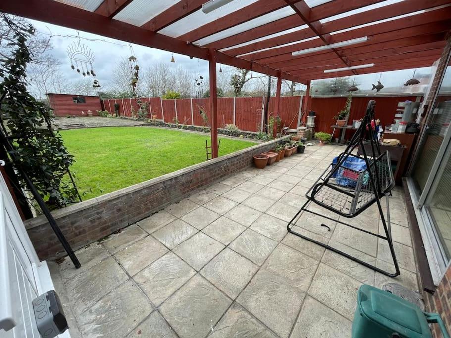 a patio with awning and a garden with a lawn at Whole Flat Close To Wembley in Wealdstone