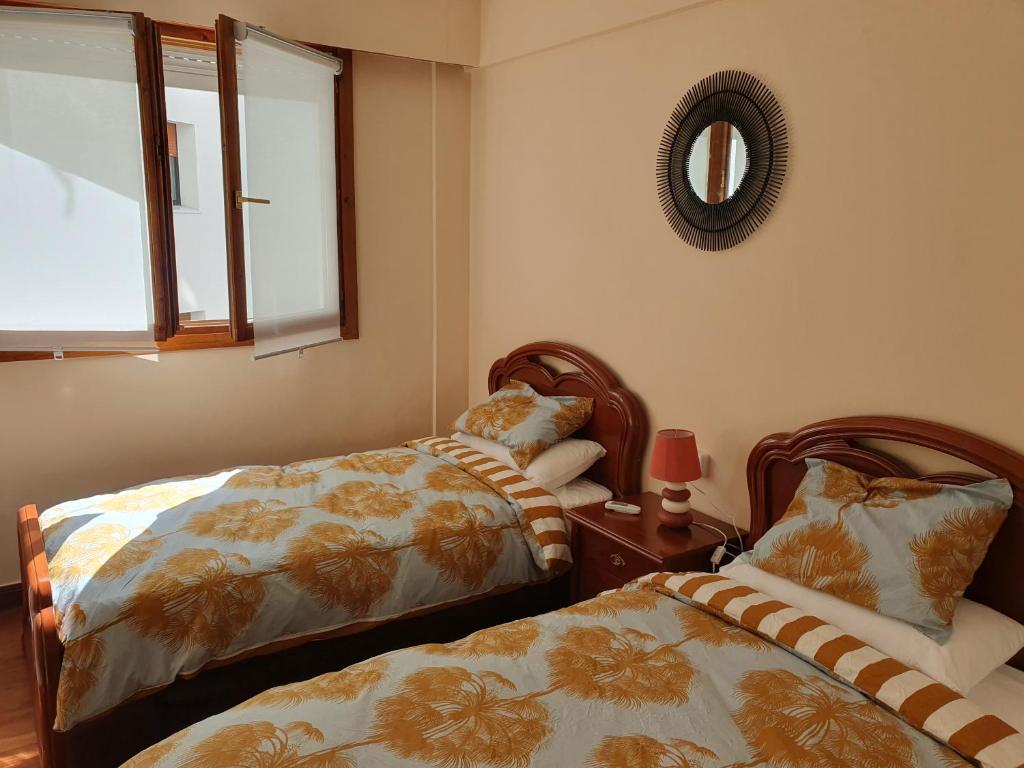 a bedroom with two beds and a mirror on the wall at Apartamento en la costa in Lekeitio