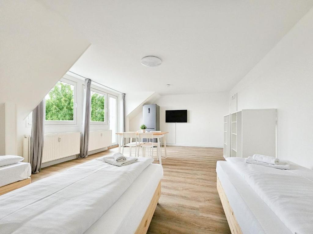 een witte kamer met 2 bedden en een tafel bij RAJ Living - 3 Zimmer Wohnung mit Balkon - 25 Min zur Messe DUS in Heiligenhaus