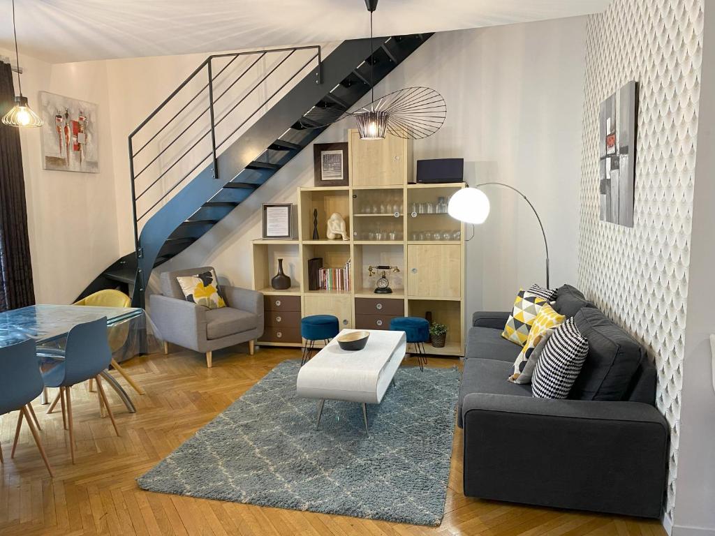 - un salon avec un canapé noir et un escalier dans l'établissement La Bonneterie grand appartement Part Dieu de charme pour 8 personnes, à Lyon