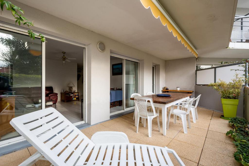 patio con sillas blancas, mesa y comedor en Evasion et detente sur le Bassin d Arcachon, en Andernos-les-Bains