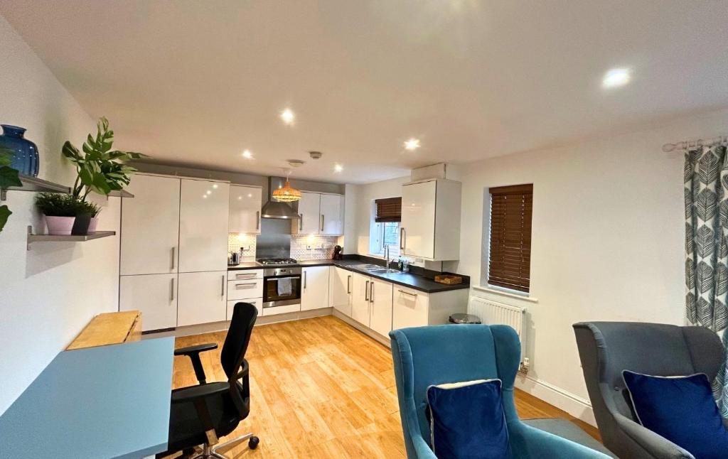 a kitchen with white cabinets and blue chairs at Wokingham Spectacular 2 Bedroom Penthouse in Bracknell