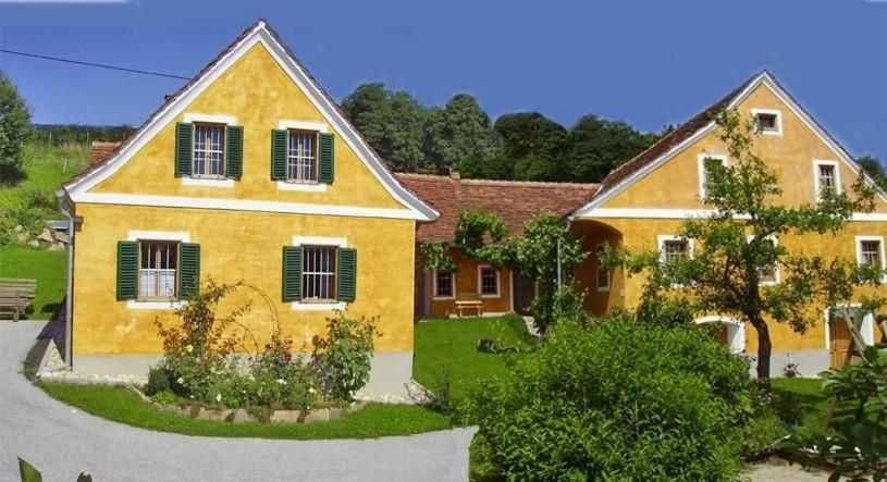 une maison jaune avec volets verts dans l'établissement Bauernhaus Posch, Ferienappartements, 