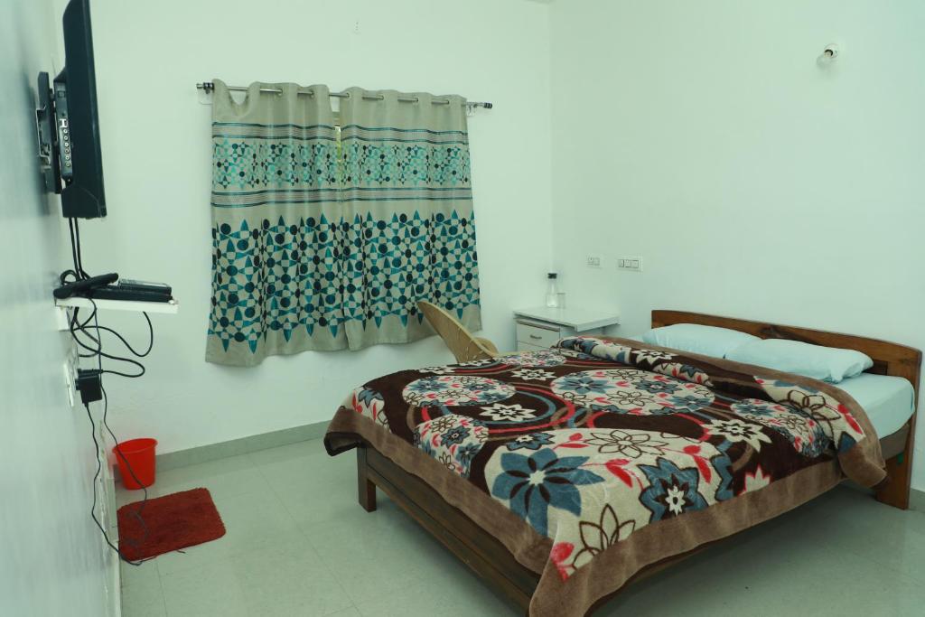 a bedroom with a bed and a curtain and a television at dreams cottage in Ooty
