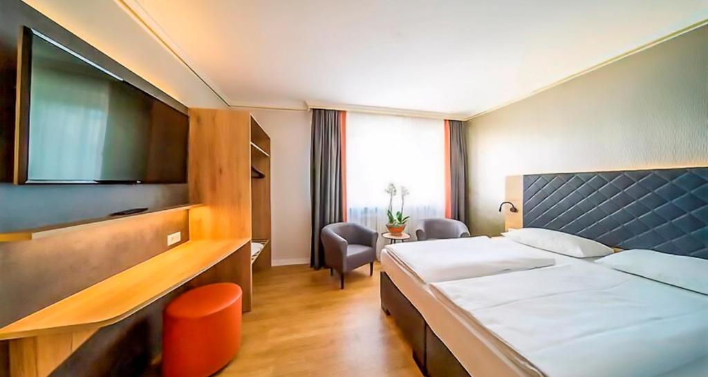 a hotel room with a bed and a tv at PLAZA INN Rieker Stuttgart Hauptbahnhof in Stuttgart