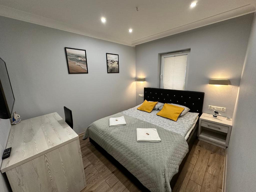 a bedroom with a bed with two yellow pillows at Maximus Apartamenty in Ustka