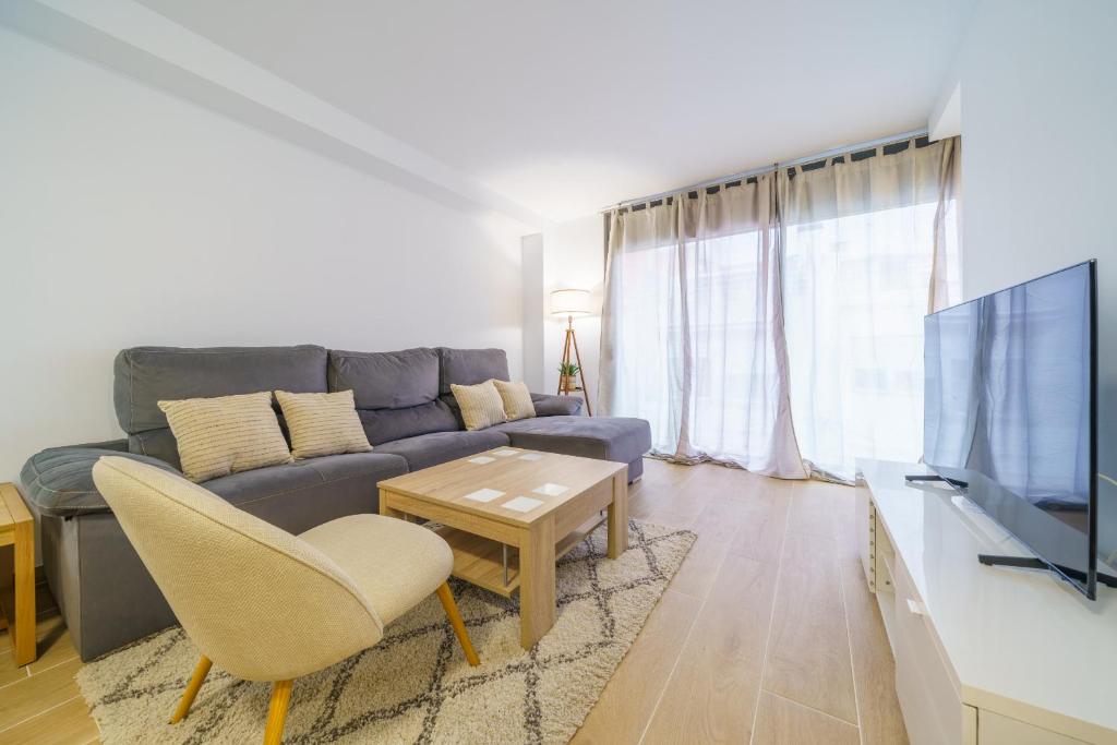 ein Wohnzimmer mit einem Sofa und einem TV in der Unterkunft HomeHolidaysRentals Zen - Costa Barcelona in Pineda de Mar
