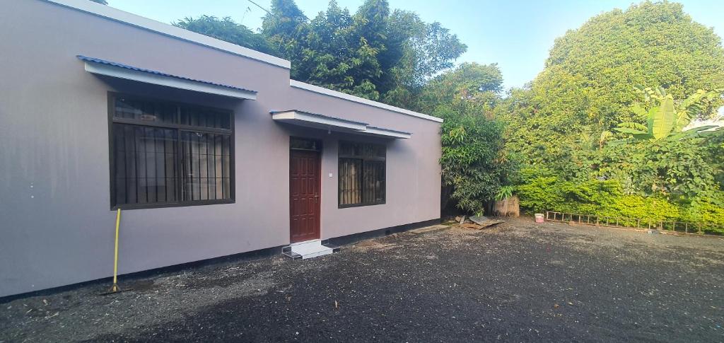 ein weißes Haus mit einer roten Tür und einigen Bäumen in der Unterkunft Orchard Residence Arusha in Arusha