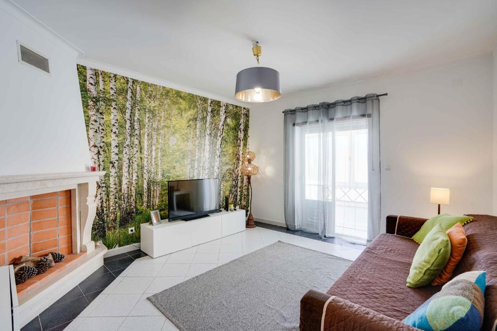 a living room with a couch and a tv at Peniche Sun & Surf Apartment in Peniche