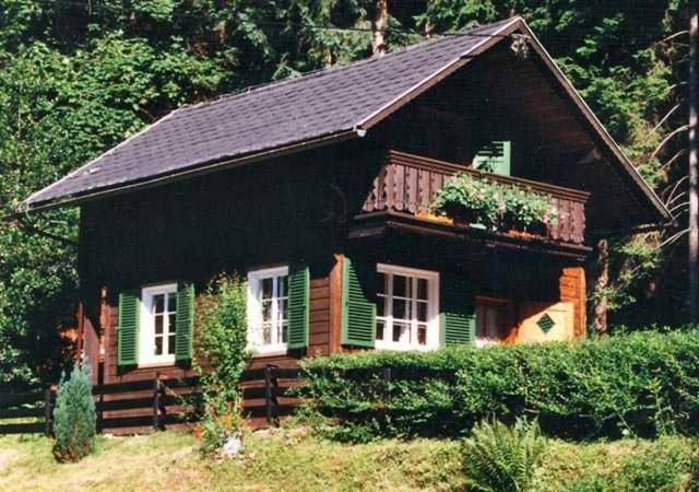 uma pequena casa com persianas verdes em Ferienhaus Pilz Marion em Bad Goisern