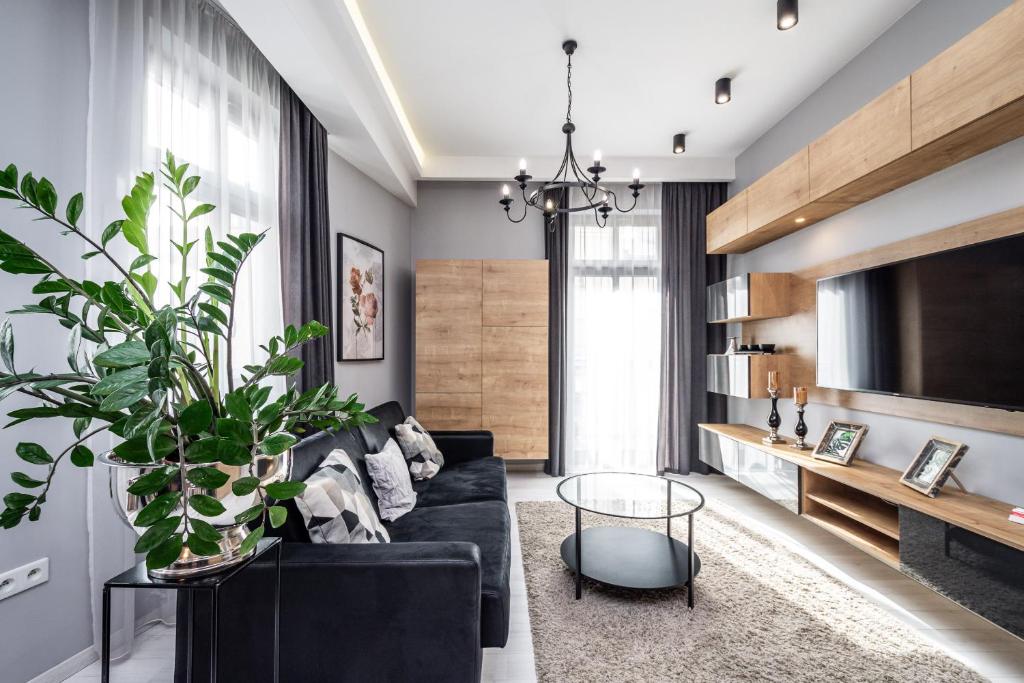 a living room with a black couch and a potted plant at RentPlanet - Apartament Wieliczka in Wieliczka