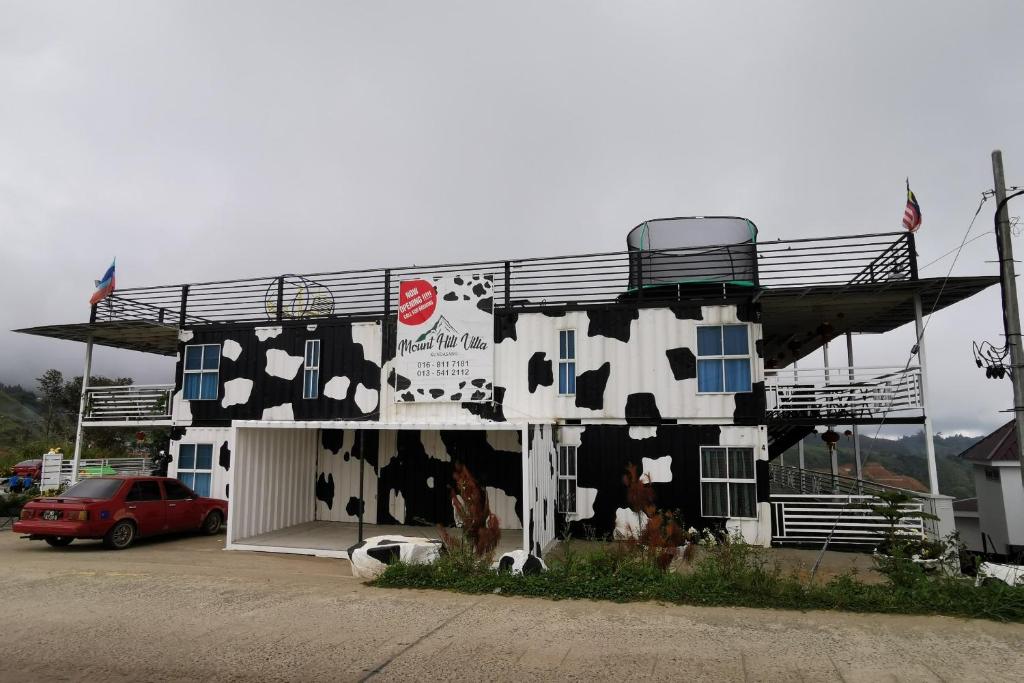 um edifício com vacas pintadas ao lado dele em OYO 89969 Mount Hill Villa Kundasang em Ranau