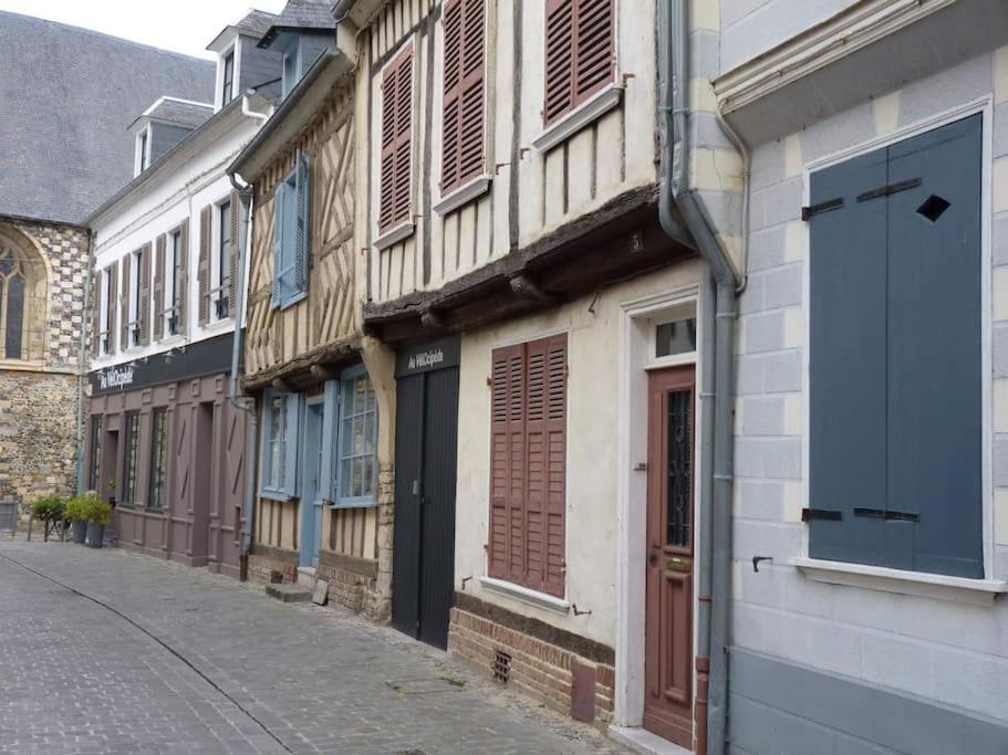 une ruelle avec des bâtiments et une porte bleue dans une rue dans l'établissement Les Valéricaines - Studio en plein cœur de la cité médiévale, à Saint-Valery-sur-Somme