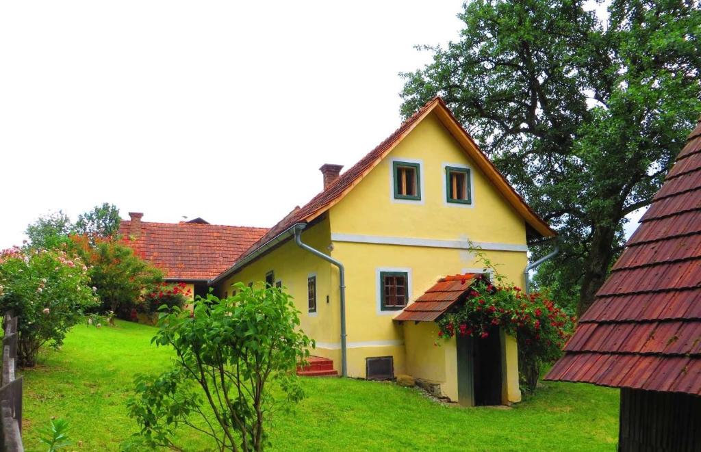 a yellow house with a red roof on a green field at Ferienhaus Baumgarten1 in Gnas